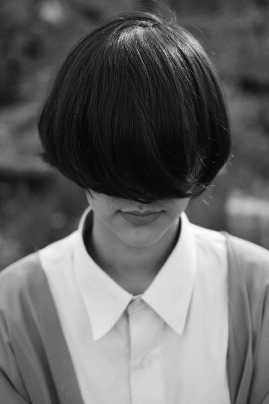 woman with cropped hair covering her face